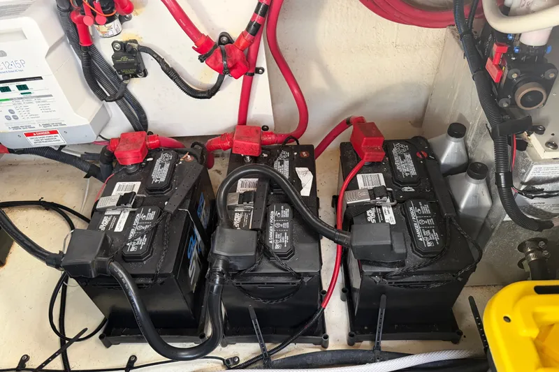 Slide: The Image of Three black batteries are installed in a boat engine compartment, surrounded by cables and switches. - 44