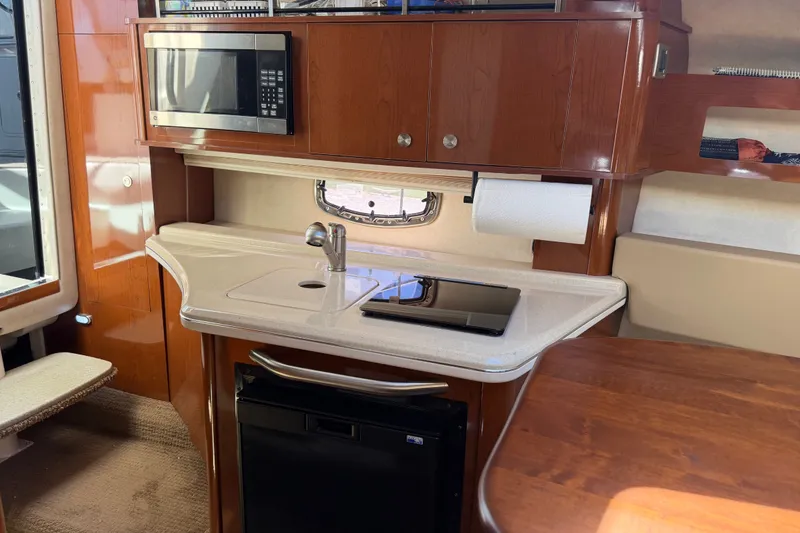 Slide: The Image of 2013 Sea Ray Sundancer 280 interior kitchen with microwave, sink, and wooden cabinetry. - 28