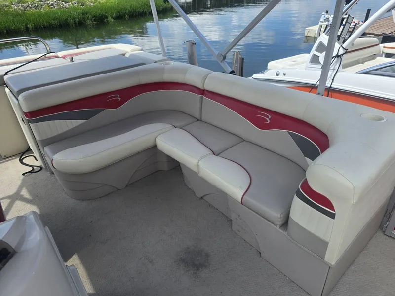 Slide: The Image of The image shows the seating area of a 2009 Bennington 2275SL. It features cream upholstery with red and gray accents. - 6