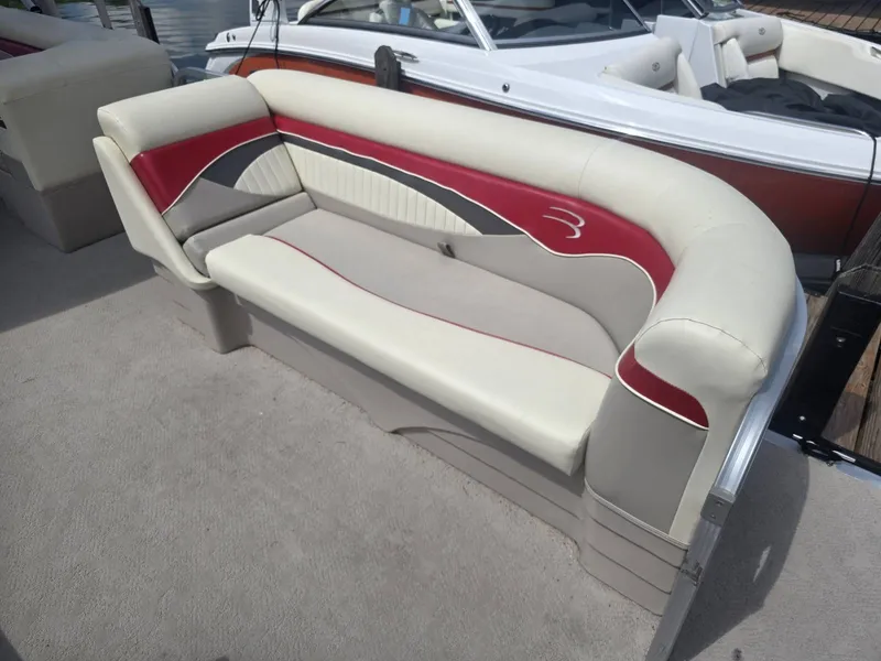 Slide: The Image of A stylish bench seat on a 2009 Bennington 2275SL pontoon boat, featuring cream and red upholstery. - 4
