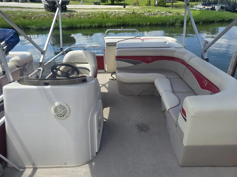 Slide: The Image of The image shows the interior of a 2009 Bennington 2275SL pontoon boat with white and red seating. - 5