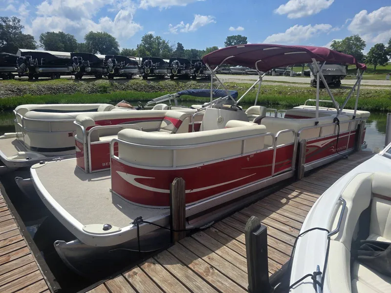Slide: The Image of A red 2009 Bennington 2275SL pontoon boat is docked at a wooden pier. It features a sunshade. - 2
