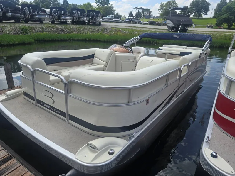 The Image of A 2008 Bennington 2050GL pontoon boat docked. It features white upholstery and an open deck. - 1