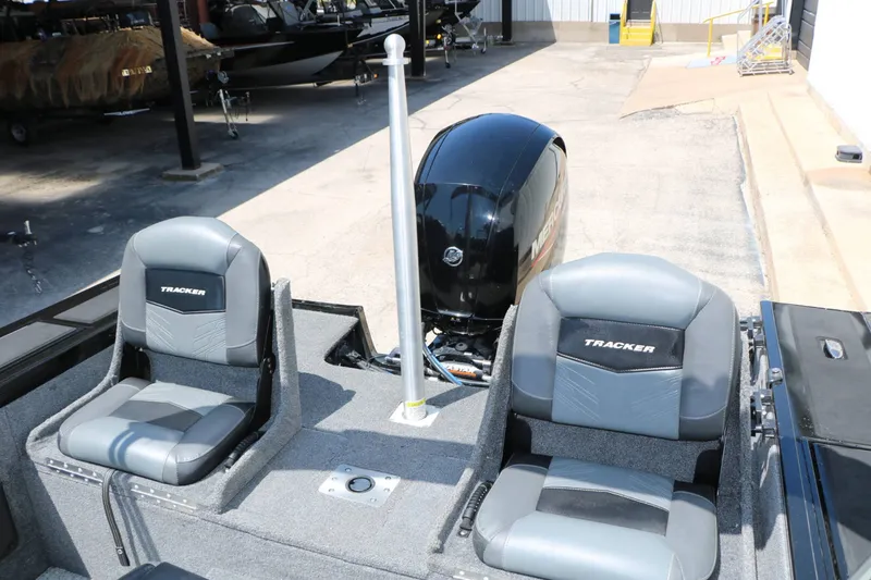 Slide: The Image of Two gray seats with "Tracker" logo on a boat, with an outboard motor in the background. - 45