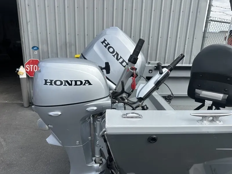 Slide: The Image of Two Honda outboard motors are mounted on a gray boat, positioned in front of a corrugated metal building. - 2