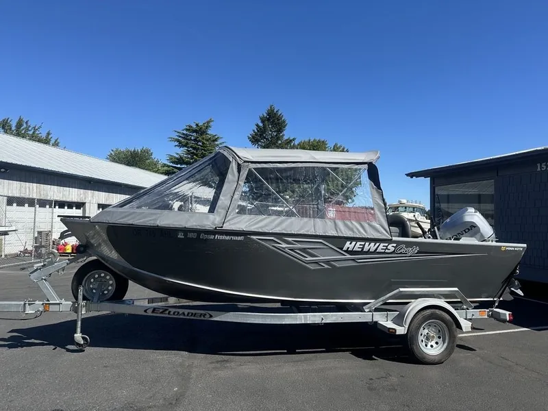 Slide: The Image of 2021 Hewescraft Open Fisherman 180 OF on a trailer, with a gray canopy, parked outdoors. - 10