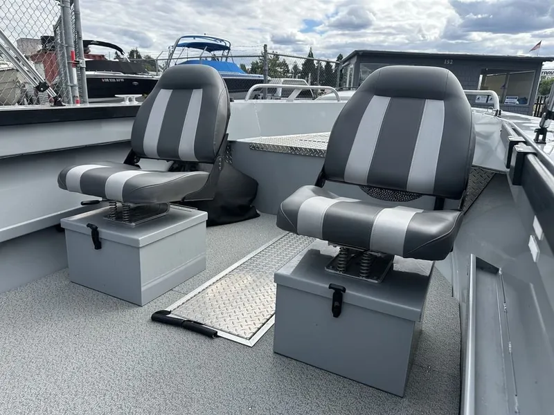 Slide: The Image of Two cushioned seats with gray and white stripes in an open boat. Metal flooring and gray walls. - 7
