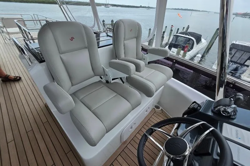 Slide: The Image of Luxurious helm seats on 2024 Sirena 58 Flybridge MY yacht, overlooking marina. - 52