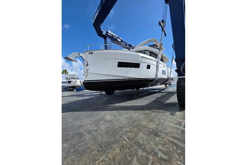 Slide: The Image of 2024 Sirena 58 Flybridge MY yacht being lifted by crane under clear blue sky. - 131