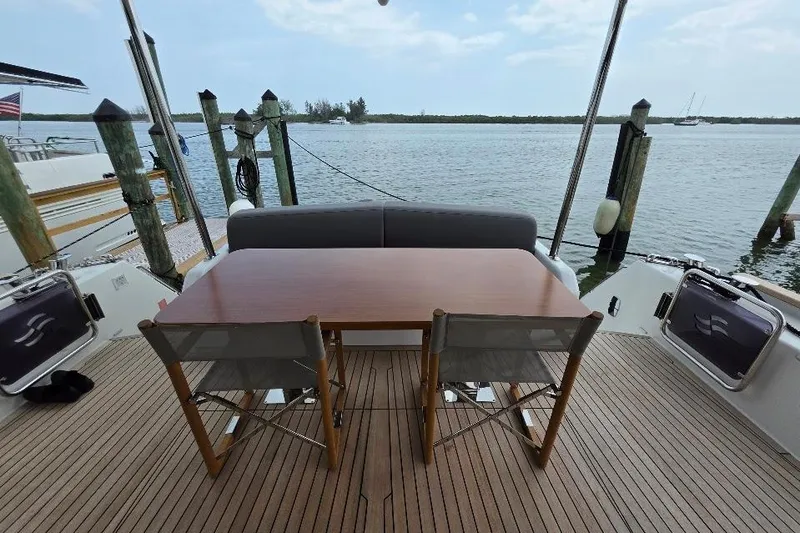 Slide: The Image of Flybridge yacht deck with table and chairs, overlooking serene waters. Sirena 58 FLYBRIDGE MY 2024. - 13