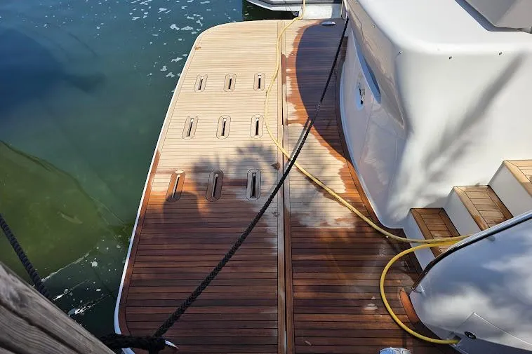 Slide: The Image of 2024 Sirena 58 Flybridge MY yacht with teak swim platform and steps, docked by the water. - 8