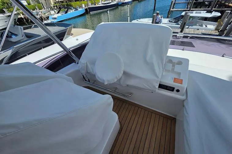 Slide: The Image of 2024 Sirena 58 Flybridge MY yacht helm with protective covers, docked at marina. - 30