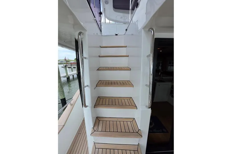 Slide: The Image of Staircase on 2024 Sirena 58 Flybridge MY yacht, featuring sleek wooden steps and stainless steel railings. - 25
