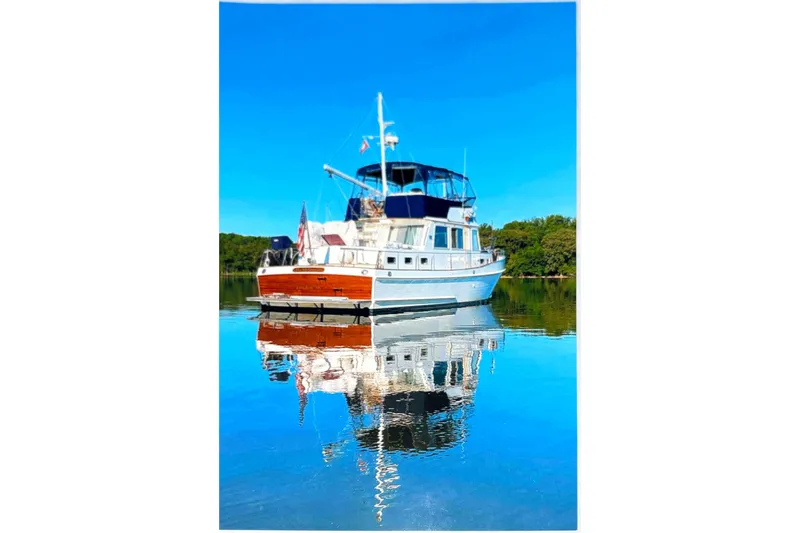 The Image of Grand Banks 46 Classic 2004 yacht reflecting on calm water under clear blue sky. - 1