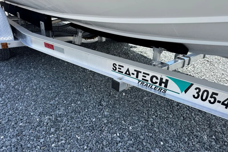 Slide: The Image of Trailer for 2023 Hurricane SunDeck 2410 OB boat on gravel surface. - 7