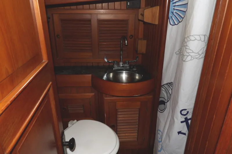 Slide: The Image of Wood-paneled bathroom in 1986 Hans Christian 43 T yacht with sink and nautical-themed curtain. - 47