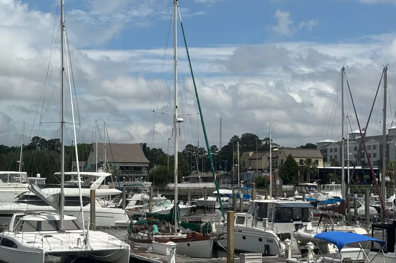 Slide: The Image of Marina with various sailboats, including a 1986 Hans Christian 43 T, under a partly cloudy sky. - 55