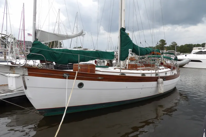 The Image of 1986 Hans Christian 43 T sailboat docked in marina, featuring classic wooden design and green covers. - 0
