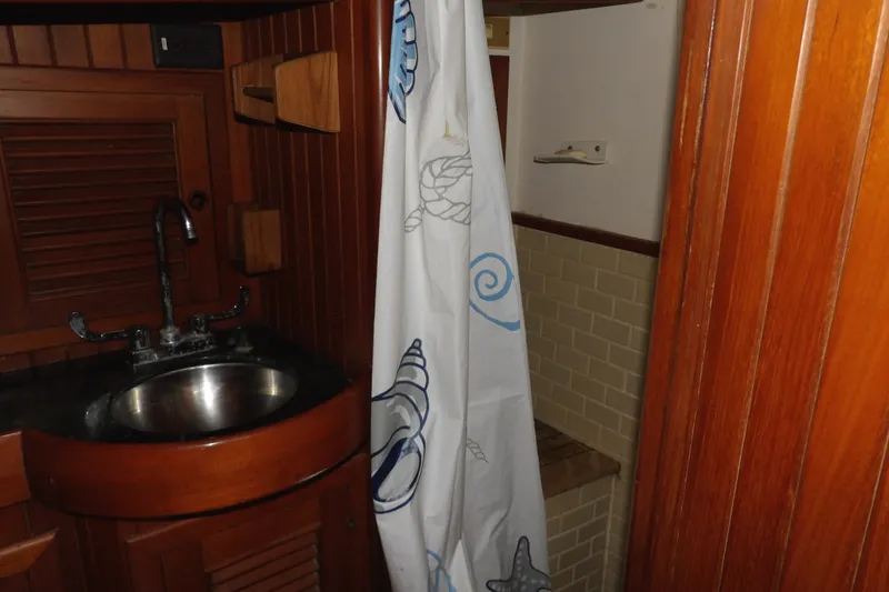 Slide: The Image of 1986 Hans Christian 43 T yacht bathroom with wooden cabinetry and nautical-themed shower curtain. - 48