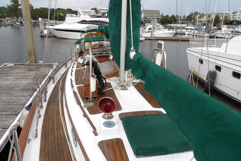 Slide: The Image of 1986 Hans Christian 43 T sailboat docked at marina, featuring wooden deck and green sail cover. - 26