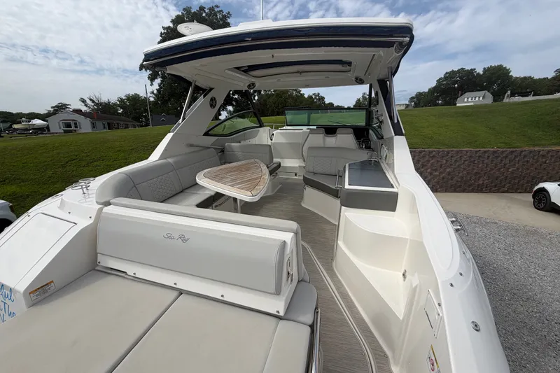 Slide: The Image of 2021 Sea Ray Sundancer 320 boat interior with seating and table, docked outdoors. - 9