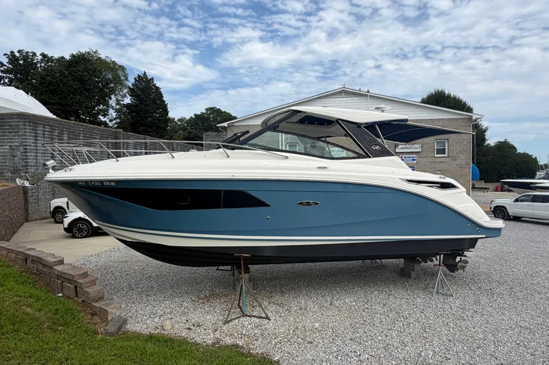 Slide: The Image of 2021 Sea Ray Sundancer 320 boat displayed on gravel lot, blue and white exterior. - 5