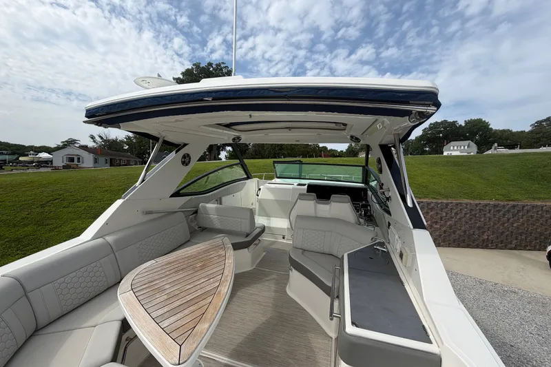 Slide: The Image of 2021 Sea Ray Sundancer 320 boat interior with seating and table, under a clear sky. - 11
