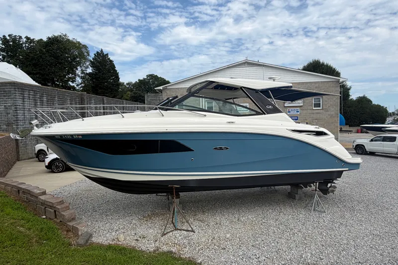 Slide: The Image of 2021 Sea Ray Sundancer 320 boat displayed on gravel lot, blue and white exterior. - 4