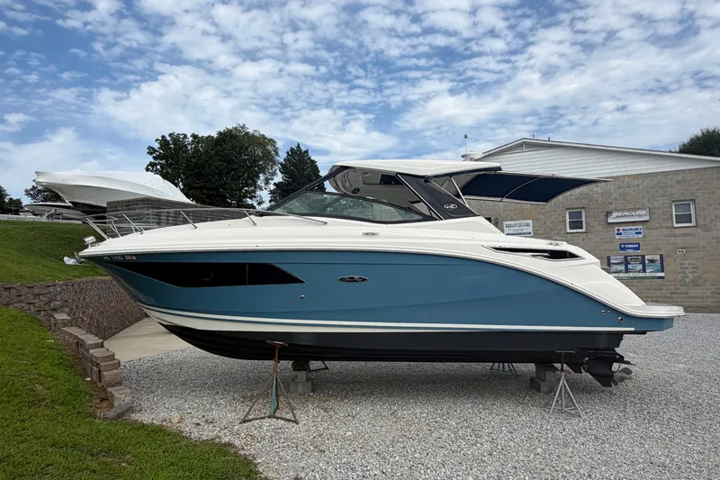 Slide: The Image of 2021 Sea Ray Sundancer 320 boat displayed on stands, under a partly cloudy sky. - 3