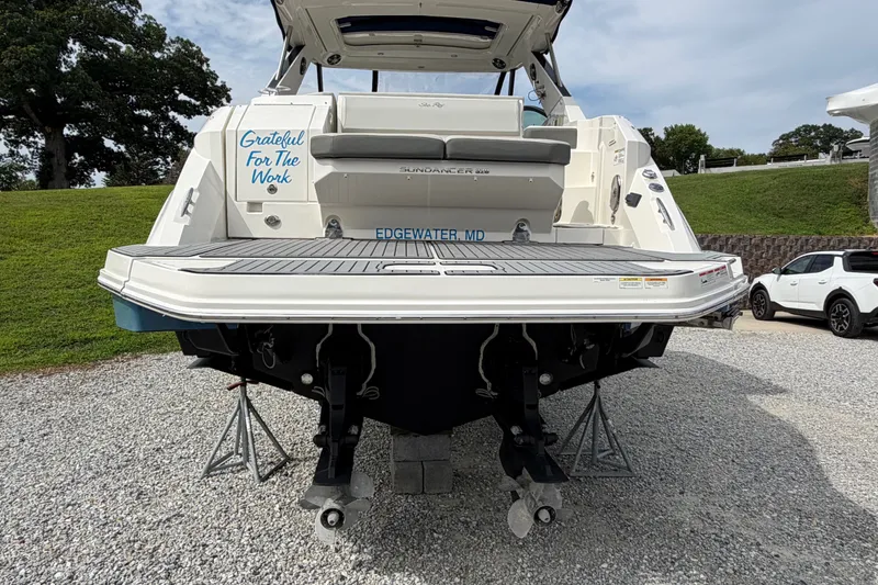 Slide: The Image of 2021 Sea Ray Sundancer 320 boat, rear view, on gravel with trees and cars nearby. - 7