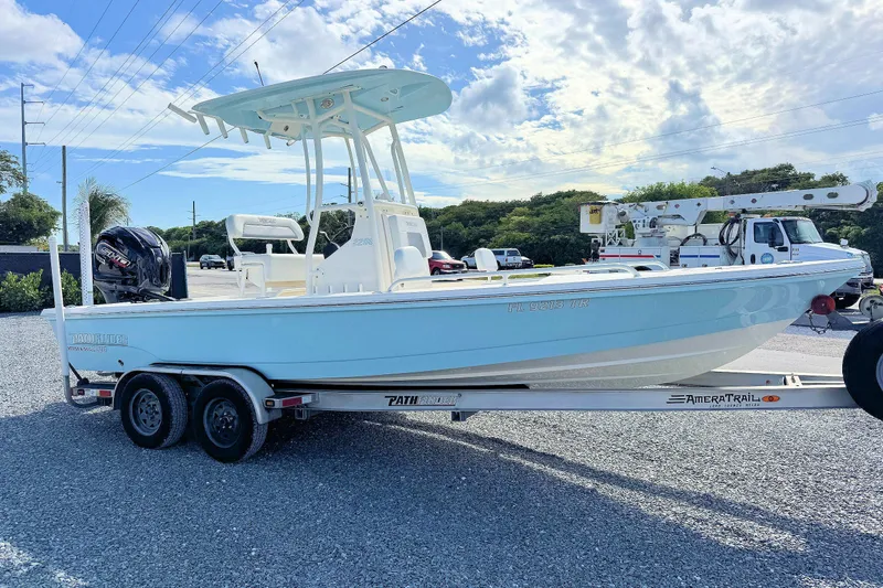 Slide: The Image of 2023 Pathfinder 2200 TRS boat on trailer, light blue hull, parked outdoors under a cloudy sky. - 4