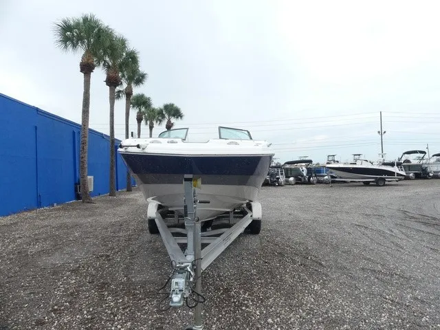 Slide: The Image of A 2023 NauticStar 243 DC boat on a trailer, surrounded by palm trees and other boats. - 3