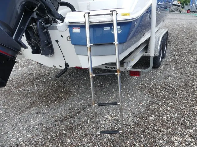 Slide: The Image of A 2023 NauticStar 243 DC with a retractable swim ladder at the stern, on a trailer. - 22