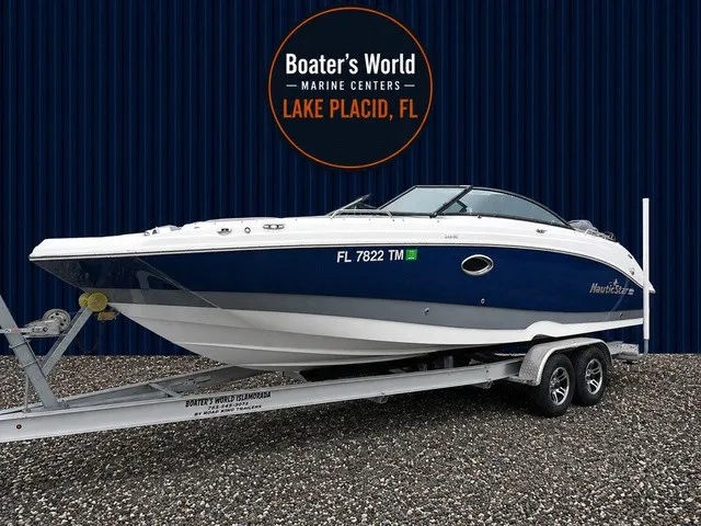 Slide: The Image of A blue and white 2023 NauticStar 243 DC boat on a trailer in front of a building. - 1