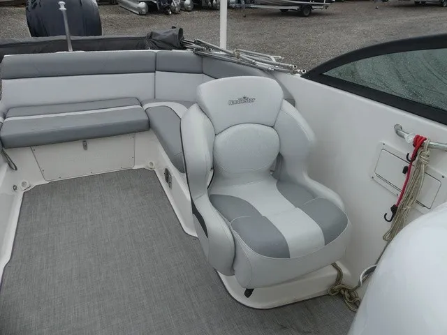 Slide: The Image of The image shows the interior of a NauticStar 243 DC boat with gray upholstery and carpeted flooring. - 17