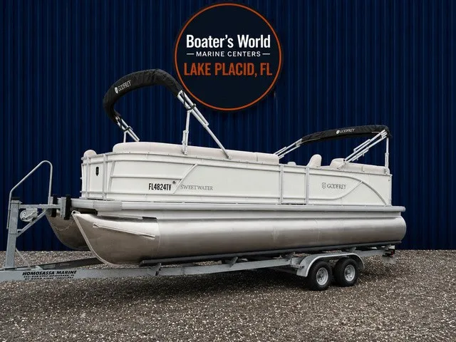 The Image of A 2024 Sweetwater SW 2286 SB pontoon boat on a trailer, set against a blue background. - 1