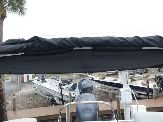 Slide: The Image of A 2024 Sweetwater SW 2286 SB with a black canopy, surrounded by other boats at a dock. - 31