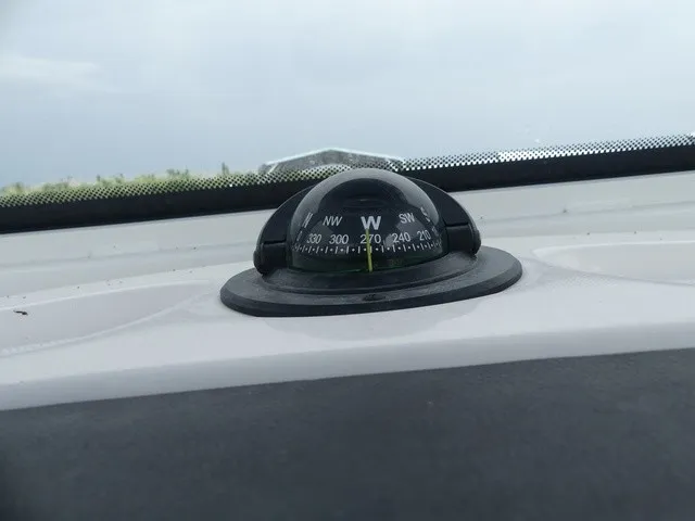 Slide: The Image of A compass on a boat points west, surrounded by a gray sky. - 23