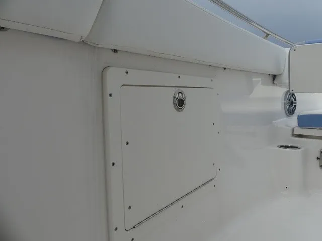 Slide: The Image of The image shows the white interior of a Robalo R272 Center Console boat with a storage compartment. - 21