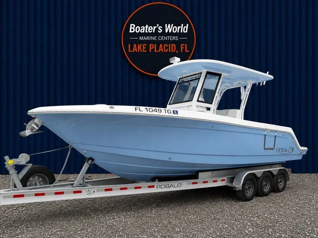 The Image of A 2022 Robalo R272 Center Console boat on a trailer against a blue background. - 1