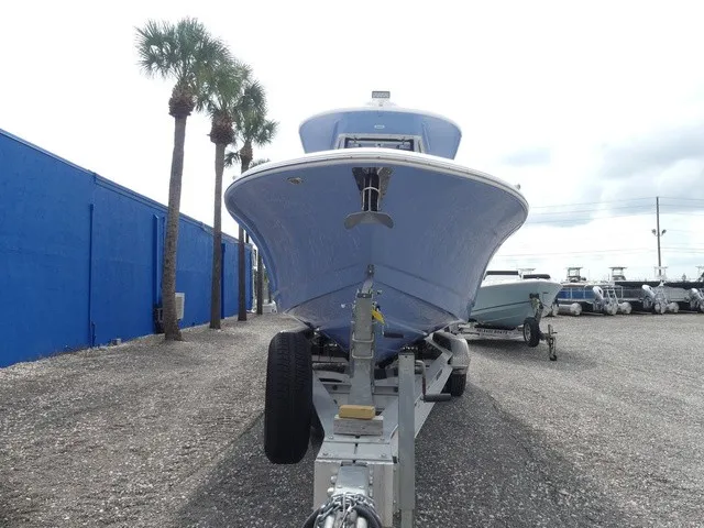 Slide: The Image of A 2022 Robalo R272 Center Console boat on a trailer, surrounded by palm trees and other boats. - 3