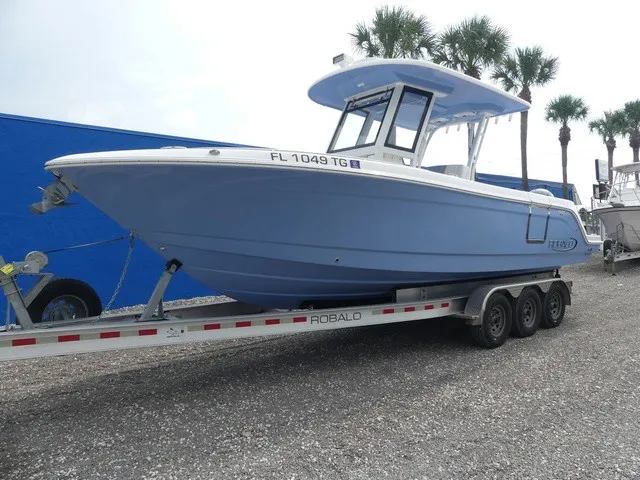 Slide: The Image of A 2022 Robalo R272 Center Console boat on a trailer, surrounded by palm trees. - 2