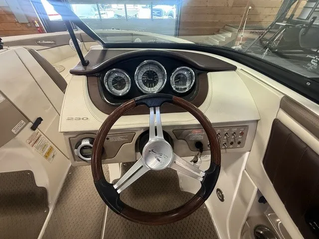 Slide: The Image of The image shows the dashboard of a 2013 Sea Ray SLX 230 boat with a sleek steering wheel and gauges. - 16