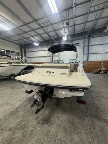 Slide: The Image of A 2013 Sea Ray SLX 230 boat is in a warehouse. It features an outboard motor. - 7