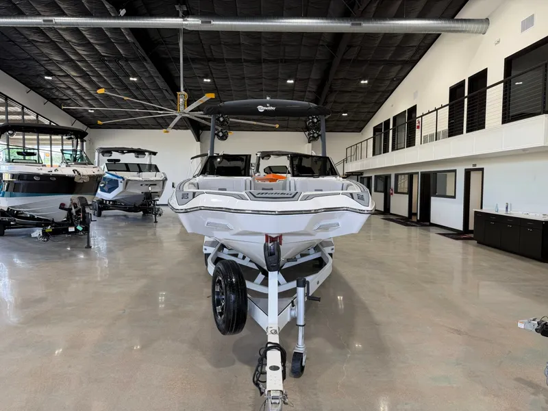 Slide: The Image of A white 2021 Malibu Wakesetter 24 MXZ boat is on a trailer in a modern showroom. - 7