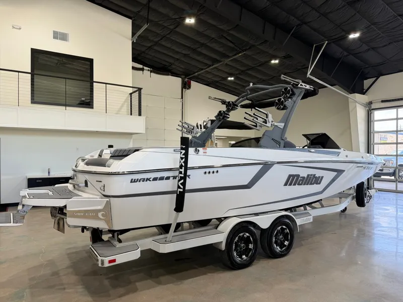 Slide: The Image of A white 2021 Malibu Wakesetter 24 MXZ boat on a trailer in a modern showroom. - 3