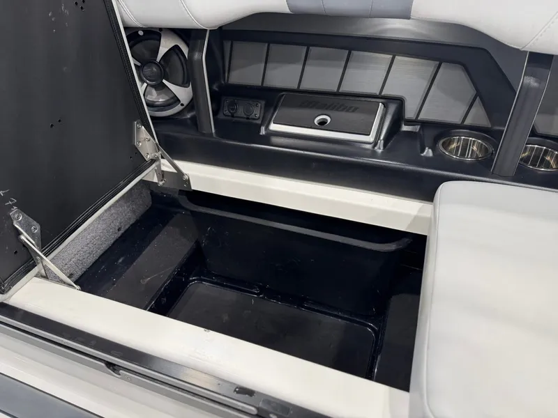 Slide: The Image of The image shows the storage area of a 2021 Malibu Wakesetter 24 MXZ with speakers and cup holders. - 18