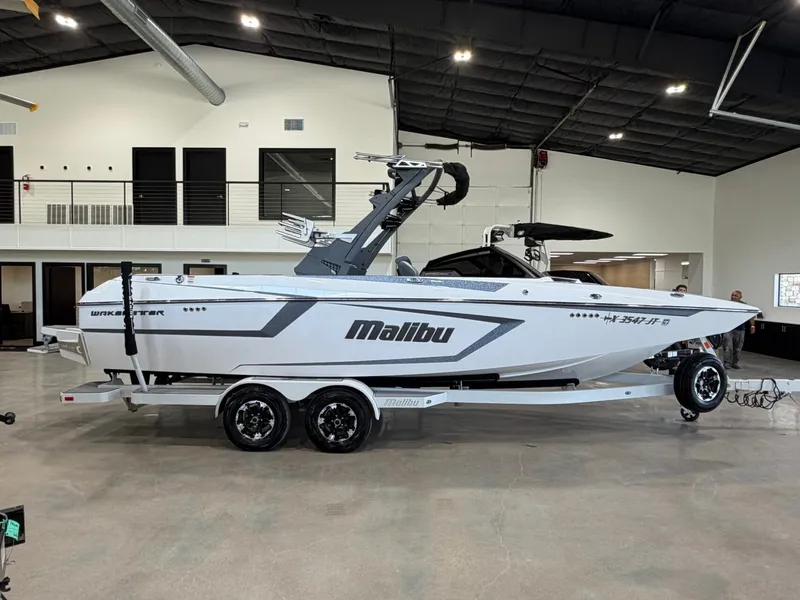 Slide: The Image of A white 2021 Malibu Wakesetter 24 MXZ boat on a trailer inside a showroom. - 2