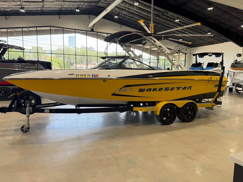 Slide: The Image of A yellow 2014 Malibu Wakesetter 24 MXZ on a trailer inside a showroom. - 7