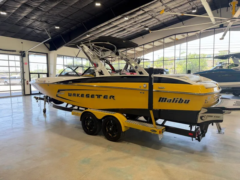 Slide: The Image of A yellow 2014 Malibu Wakesetter 24 MXZ boat on a trailer in a showroom. - 6